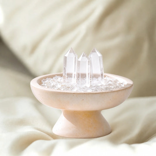 Clear crystal points arranged in a triangular grid inside a white travertine vessel